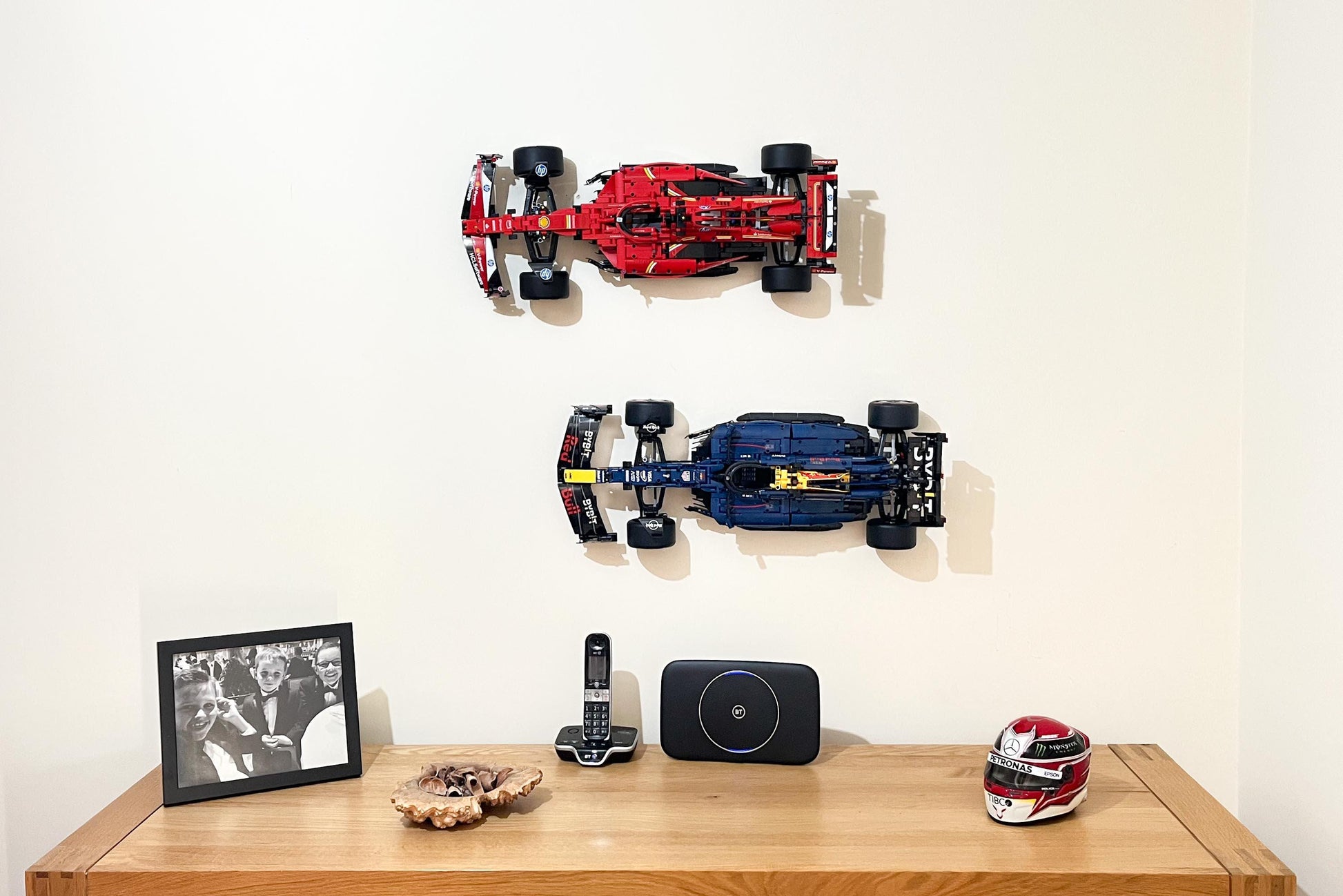 Front view  of the LEGO Technic Ferrari SF-24 F1 car (set 42207) wall mounted with the LEGO Technic Red Bull Racing Formula One car in a home study